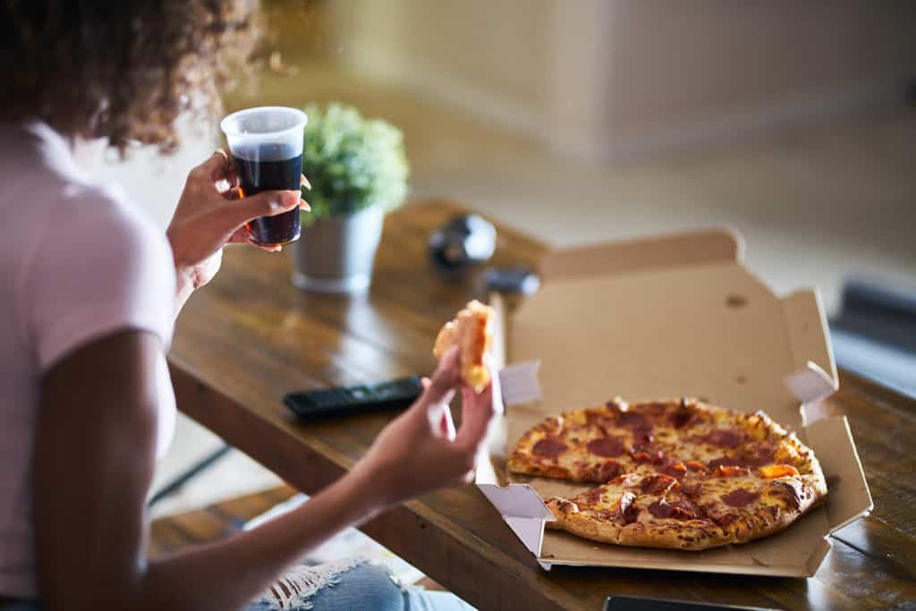 Woman eating pizza at home she got with online food ordering app