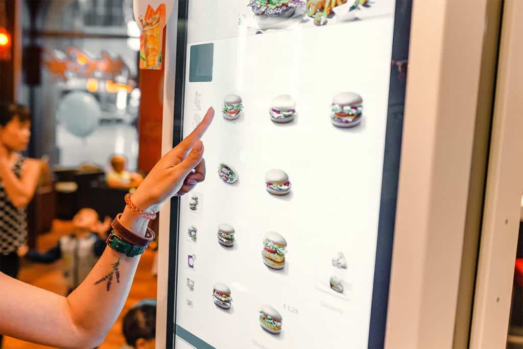 A woman orders food in the touch screen terminal with electronic menu in fast food restaurant