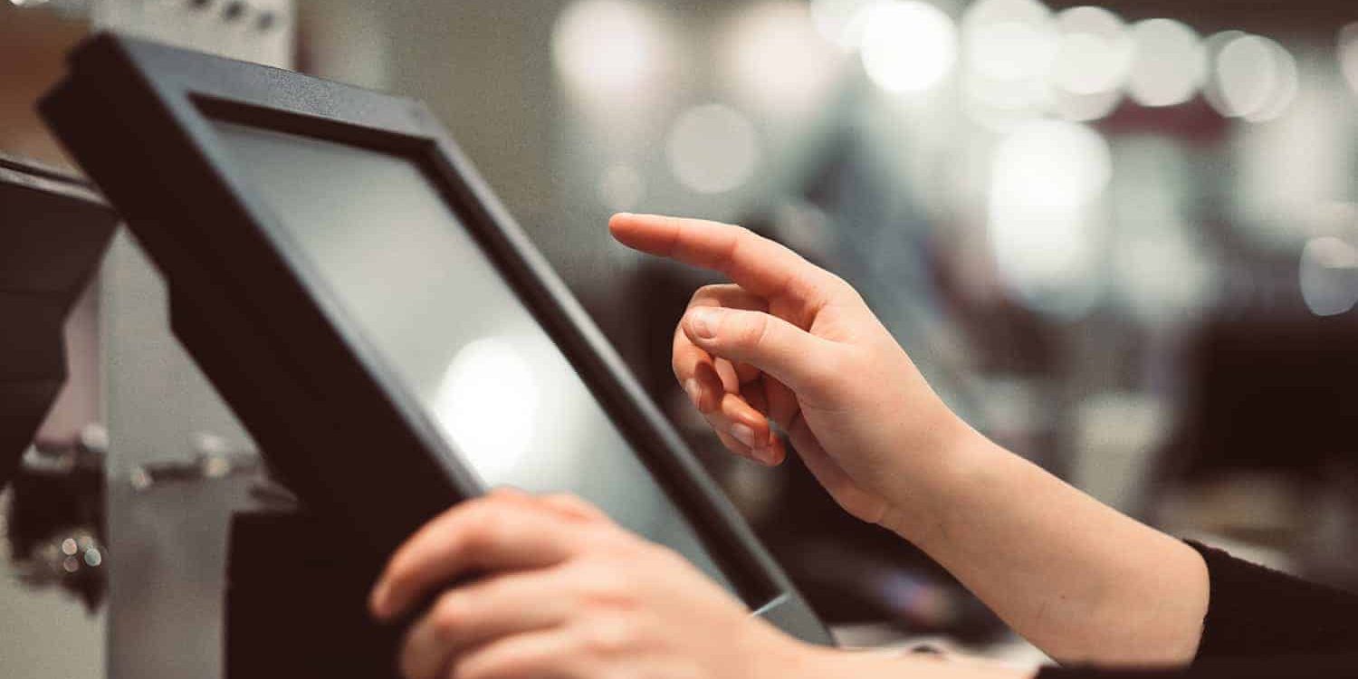 Young woman hand doing process payment on a touchscreen cash register, finance concept (color toned image)