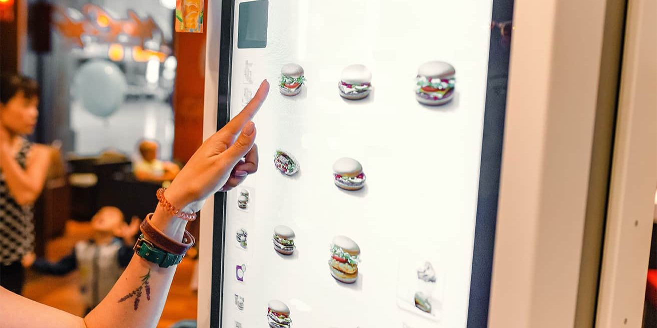 A woman orders food in the touch screen terminal with electronic menu in fast food restaurant
